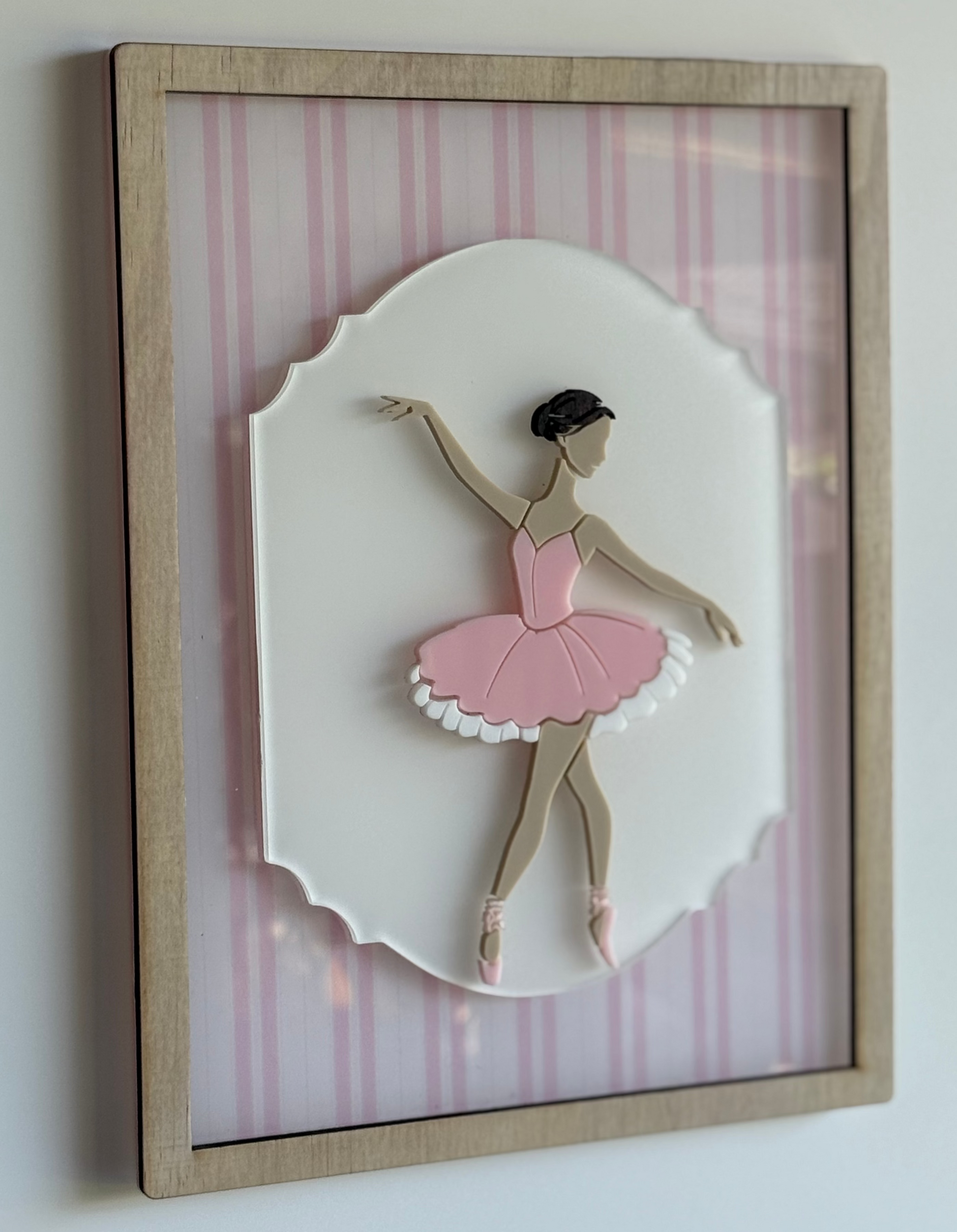 Framed artwork of a ballerina in a pink dress on a striped background