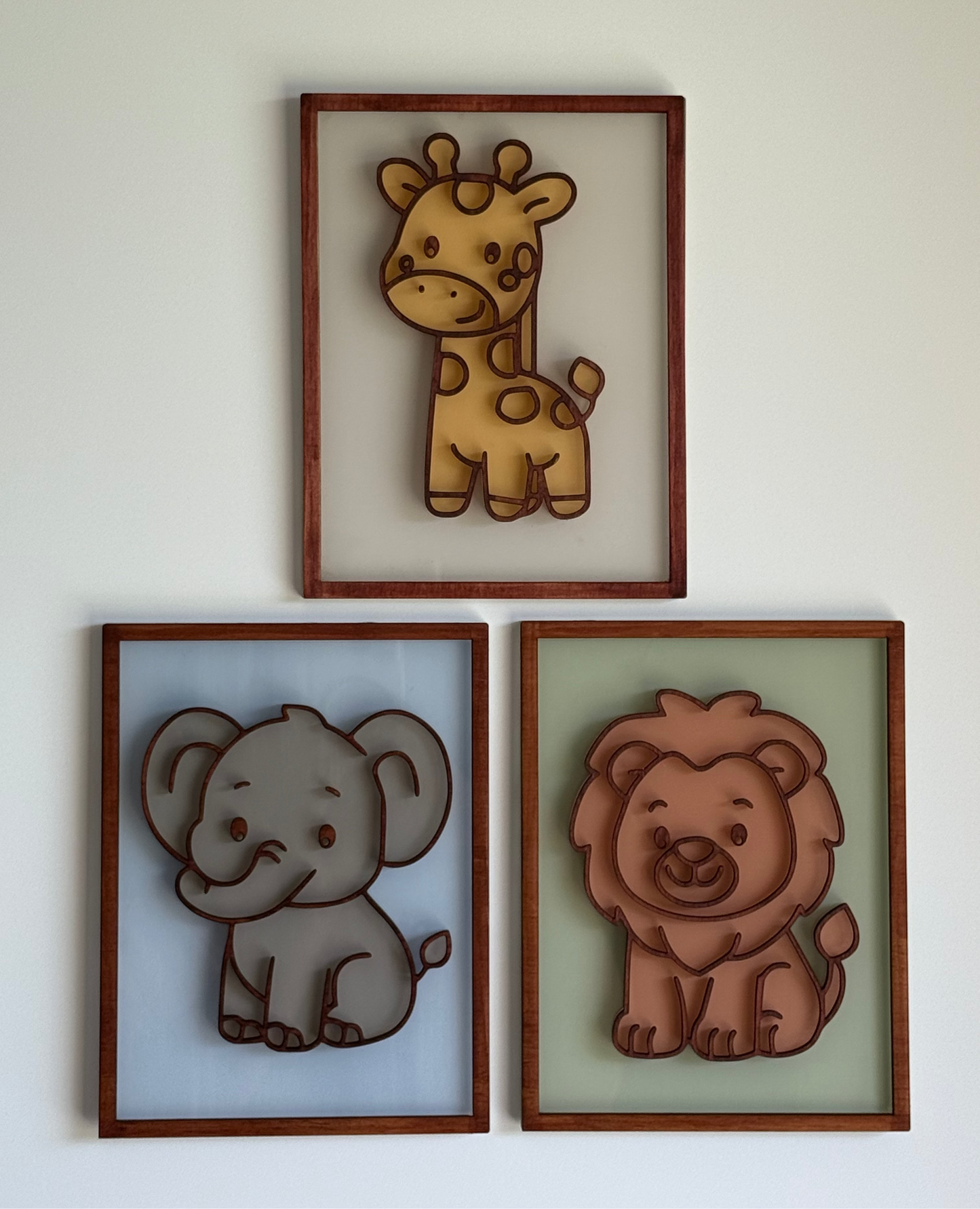 Three framed illustrations of a giraffe, elephant, and lion on a white wall.