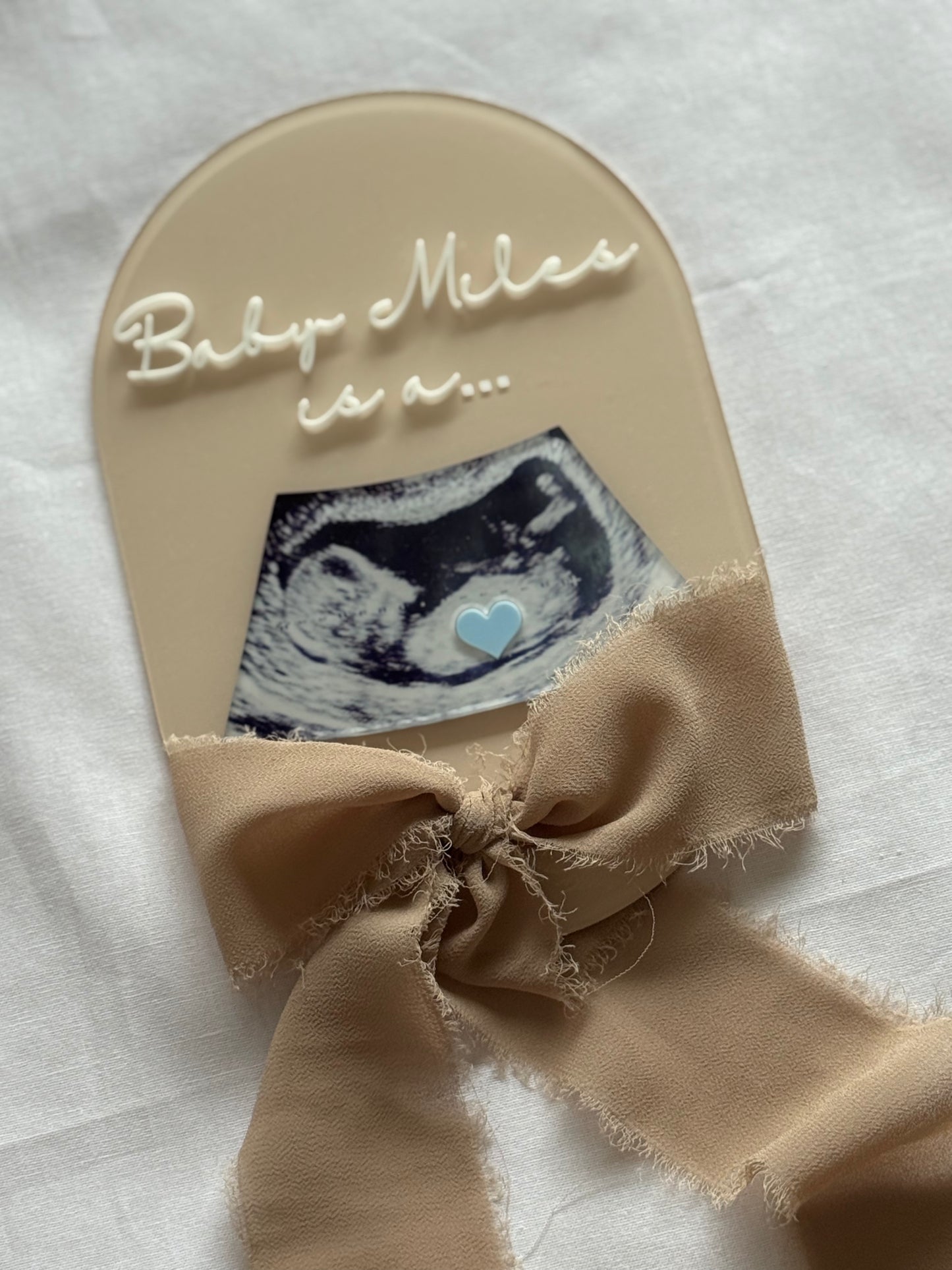 Baby shower gift with ultrasound photo and bow on a neutral background